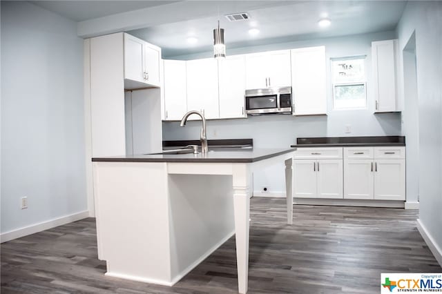 kitchen featuring a kitchen bar, dark hardwood / wood-style flooring, pendant lighting, sink, and white cabinets