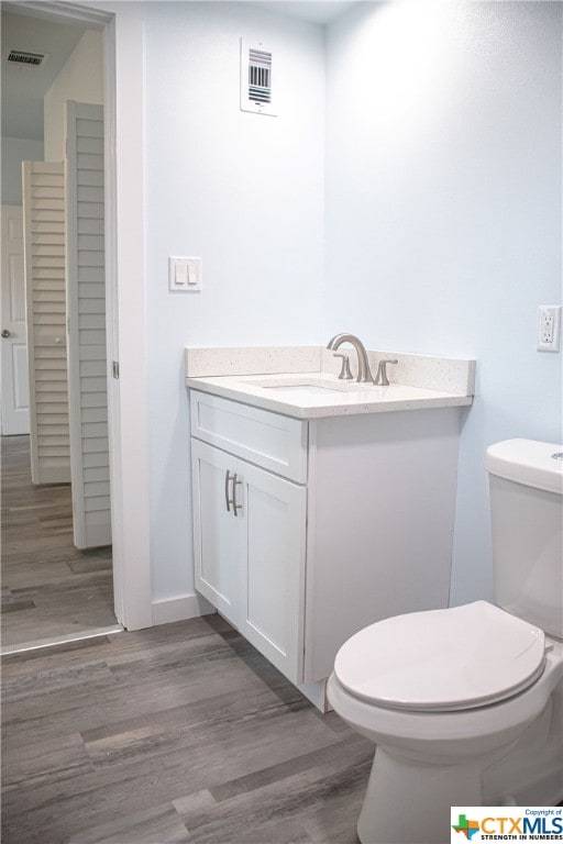 bathroom featuring toilet, vanity, and wood-type flooring