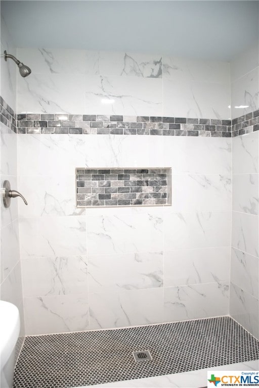 bathroom with tiled shower and toilet