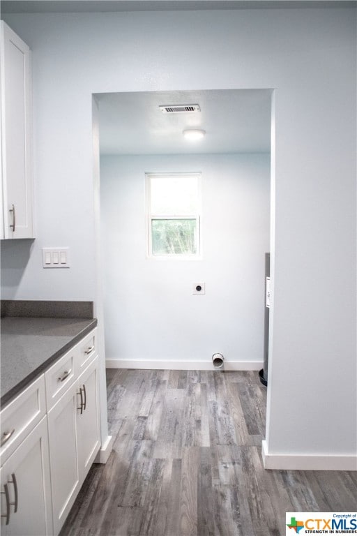 laundry room with cabinets, wood-type flooring, and hookup for an electric dryer