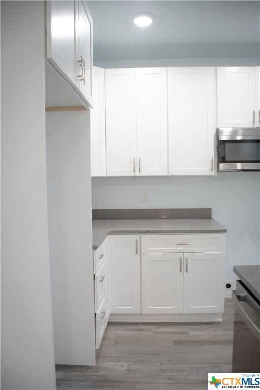 kitchen featuring white cabinets, appliances with stainless steel finishes, and light hardwood / wood-style flooring