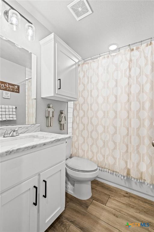 900 Holliday Dr, Killeen, TX 76542 - full bathroom featuring wood finished floors, vanity, toilet, and a shower with curtain