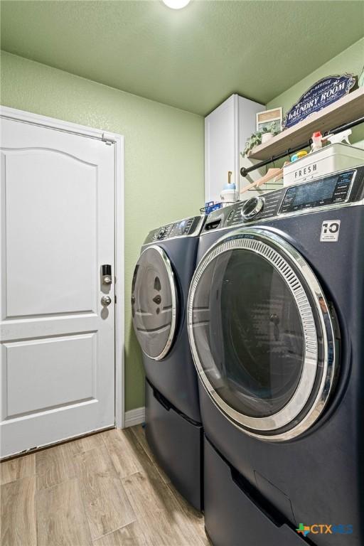 900 Holliday Dr, Killeen, TX 76542 - laundry area with cabinet space, washer and dryer, and light wood-type flooring