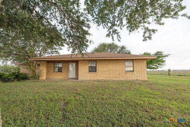 ranch-style house featuring brick siding, fence, and a front yard