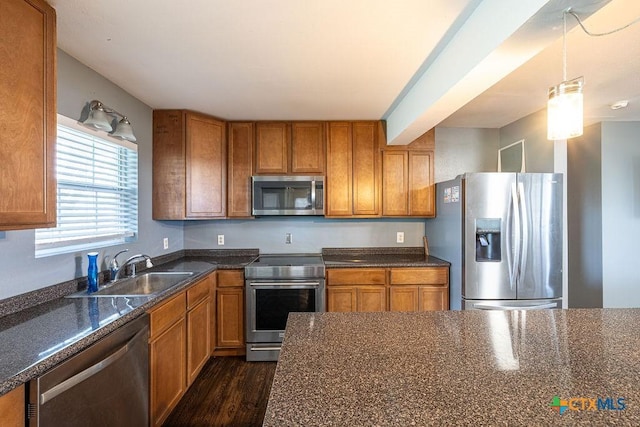 kitchen featuring a sink, dark wood finished floors, appliances with stainless steel finishes, and brown cabinets