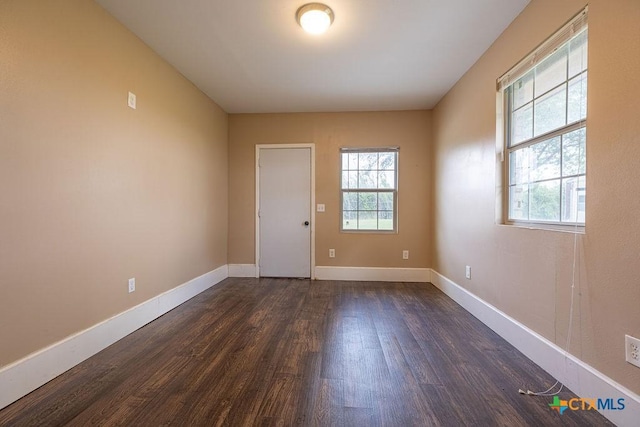 unfurnished room featuring dark wood-type flooring and baseboards