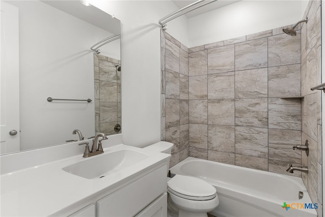 full bathroom featuring vanity, tiled shower / bath, and toilet