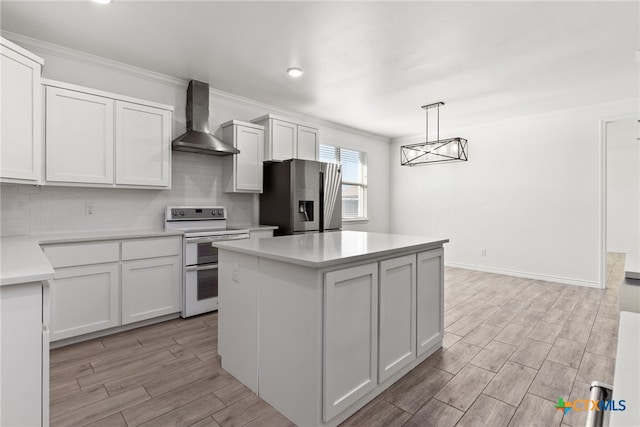 kitchen featuring hanging light fixtures, double oven range, stainless steel fridge, wall chimney range hood, and white cabinets