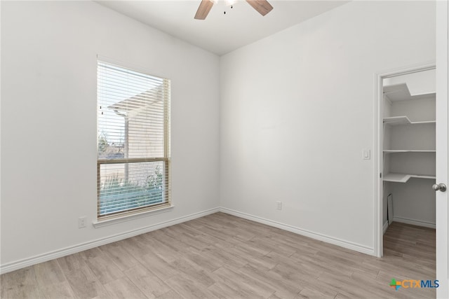 unfurnished bedroom with ceiling fan, light hardwood / wood-style floors, a closet, and a walk in closet