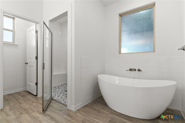 bathroom with plus walk in shower, plenty of natural light, and tile walls