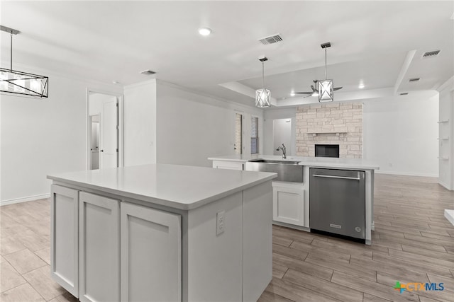 kitchen featuring stainless steel dishwasher, a tray ceiling, hanging light fixtures, and white cabinets