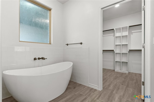 bathroom featuring hardwood / wood-style flooring and a tub to relax in