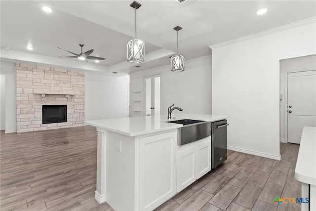 kitchen with sink, white cabinetry, decorative light fixtures, an island with sink, and a fireplace