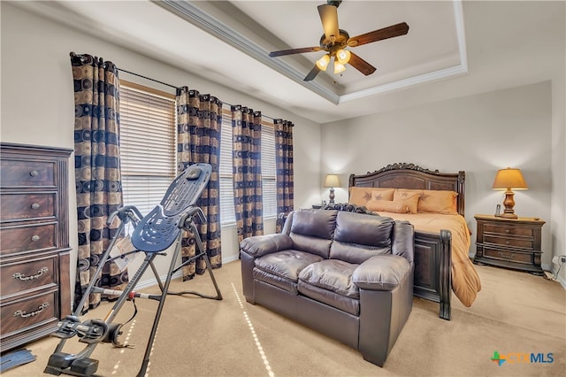 carpeted bedroom with a raised ceiling, ceiling fan, and ornamental molding