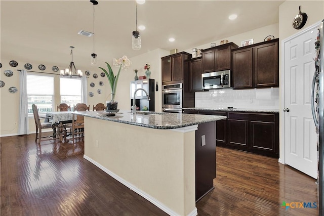 kitchen with an island with sink, sink, pendant lighting, and dark brown cabinetry