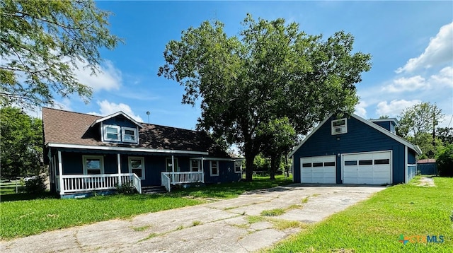 view of front of house featuring an outbuilding, a front yard, a garage, and covered porch