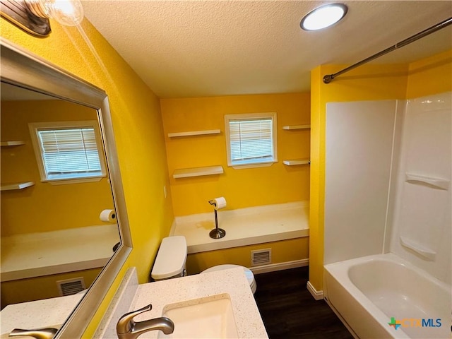 full bathroom featuring shower / bath combination, a textured ceiling, sink, hardwood / wood-style flooring, and toilet