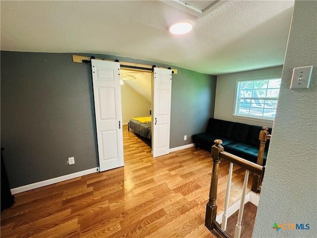 interior space with light wood-type flooring, a textured ceiling, and a barn door