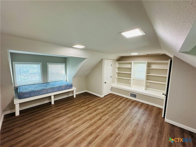 bonus room with built in shelves, lofted ceiling, a textured ceiling, and hardwood / wood-style flooring