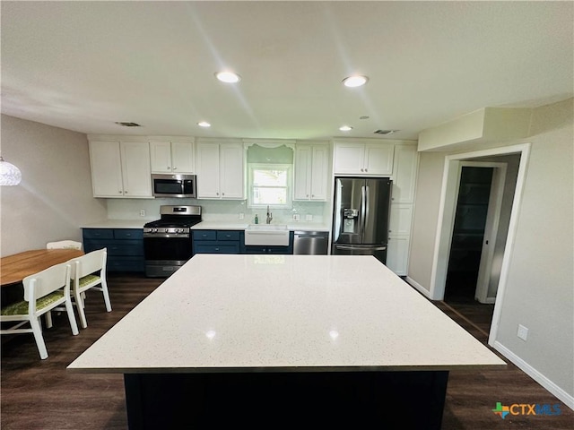 kitchen featuring white cabinets, appliances with stainless steel finishes, a center island, and sink