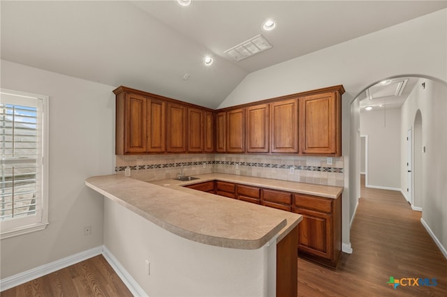 1018 Canyon Maple Rd, Pflugerville, TX 78660 - kitchen featuring light countertops, brown cabinets, dark wood-style floors, decorative backsplash, and lofted ceiling