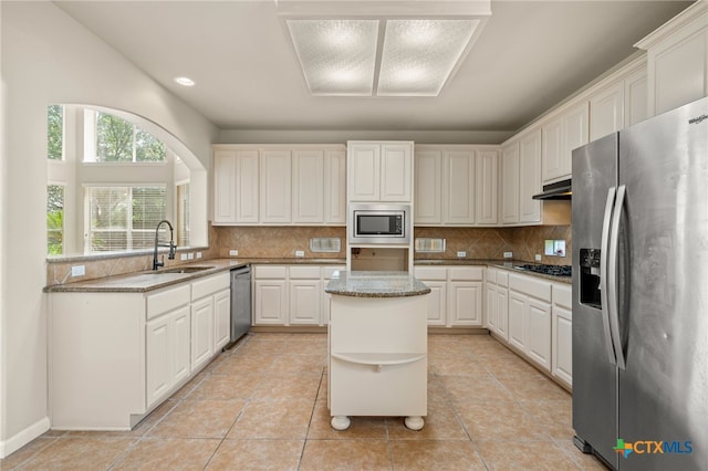 1018 Canyon Maple Rd, Pflugerville, TX 78660 - kitchen featuring stainless steel appliances, a sink, open shelves, backsplash, and light stone counters