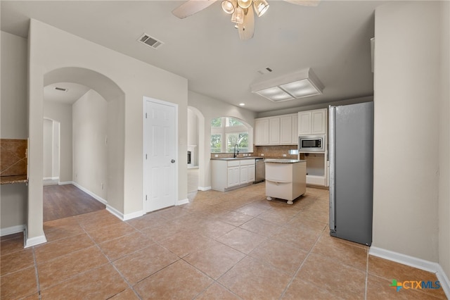 1018 Canyon Maple Rd, Pflugerville, TX 78660 - kitchen with appliances with stainless steel finishes, ceiling fan, arched walkways, light tile patterned flooring, and decorative backsplash