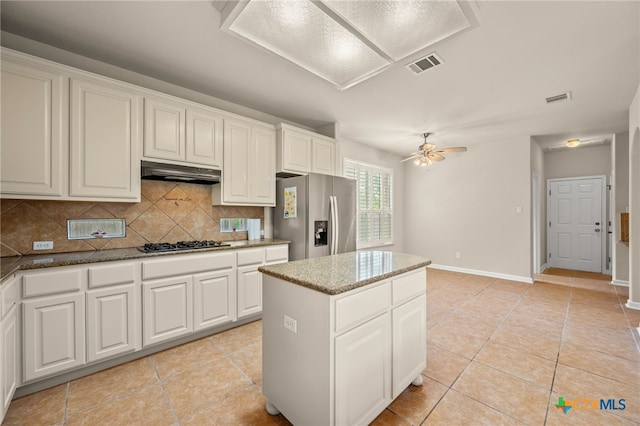 1018 Canyon Maple Rd, Pflugerville, TX 78660 - kitchen featuring stainless steel fridge with ice dispenser, under cabinet range hood, tasteful backsplash, a center island, and light tile patterned floors