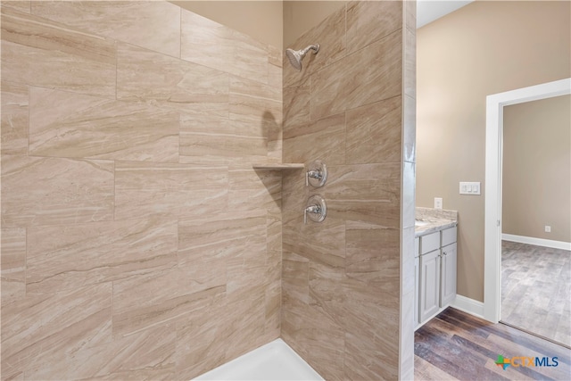 bathroom with vanity, hardwood / wood-style flooring, and a tile shower