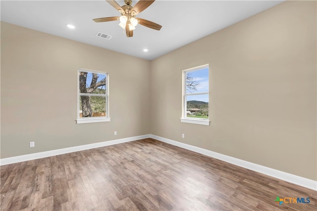 empty room featuring hardwood / wood-style flooring, a healthy amount of sunlight, and ceiling fan