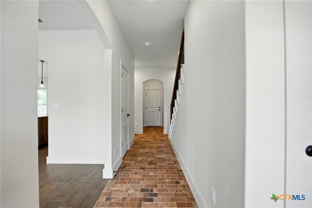 corridor featuring baseboards and arched walkways