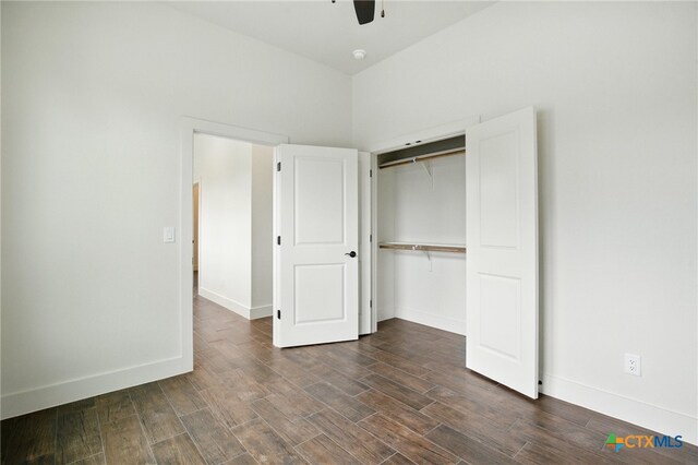 unfurnished bedroom featuring baseboards, a ceiling fan, a closet, and dark wood-style flooring