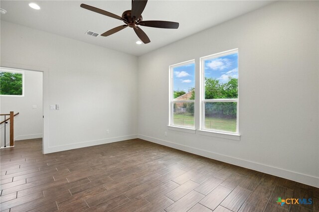 empty room featuring plenty of natural light, a ceiling fan, and dark wood-style flooring