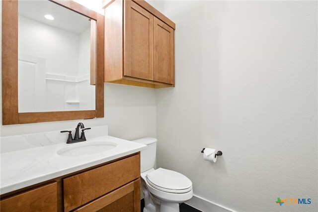 bathroom featuring toilet, baseboards, and vanity