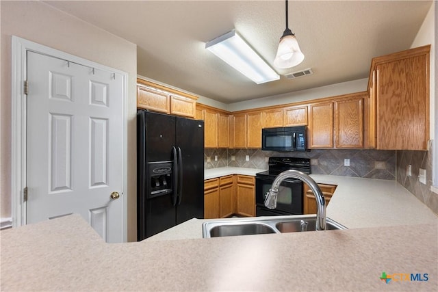 kitchen featuring sink, backsplash, decorative light fixtures, and black appliances