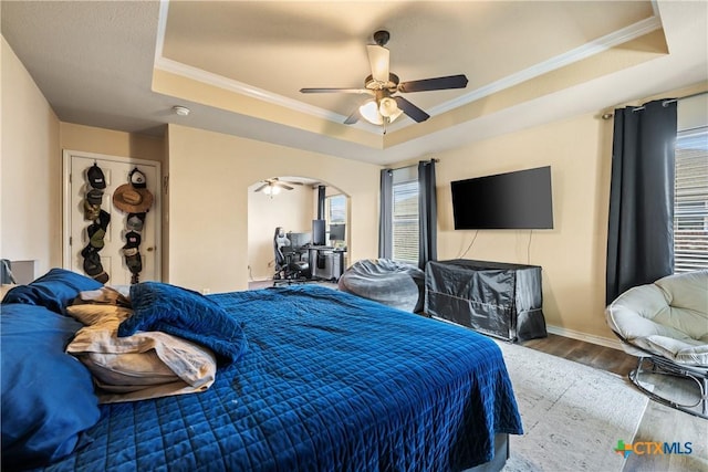 bedroom with a raised ceiling, ceiling fan, crown molding, and hardwood / wood-style flooring