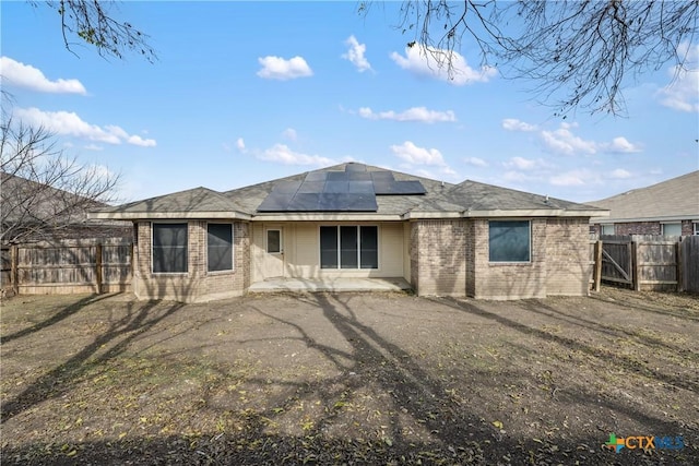 back of property with solar panels and a patio area