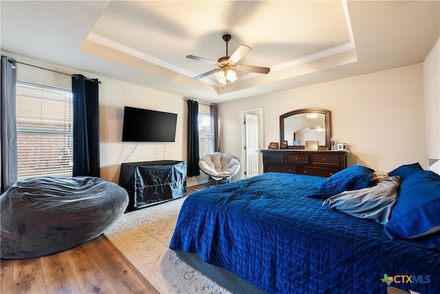 bedroom with a tray ceiling, ceiling fan, and light hardwood / wood-style floors