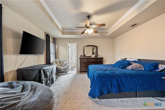 bedroom featuring ceiling fan, ornamental molding, a tray ceiling, and light hardwood / wood-style flooring