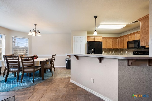 kitchen featuring a kitchen bar, decorative backsplash, black appliances, a chandelier, and hanging light fixtures