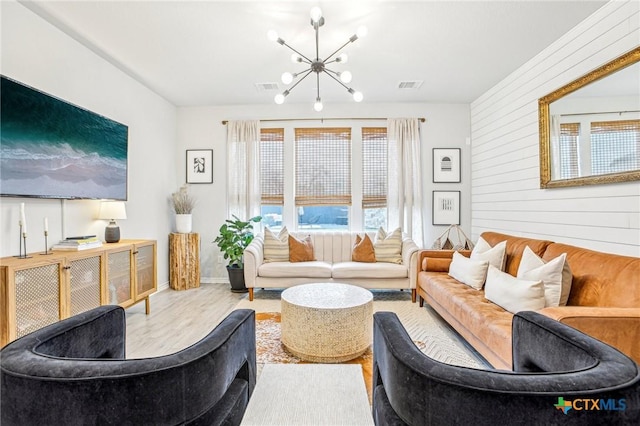 living room with wood walls, light hardwood / wood-style flooring, and a chandelier