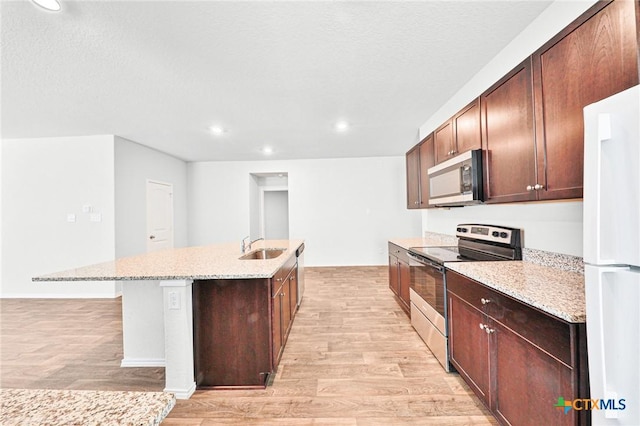 813 Indigo Way, Seguin, TX 78155 - kitchen with appliances with stainless steel finishes, light wood-style floors, a center island with sink, a sink, and recessed lighting