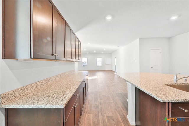 813 Indigo Way, Seguin, TX 78155 - kitchen with a sink, light wood-style flooring, recessed lighting, dark brown cabinetry, and light stone countertops