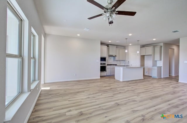 unfurnished living room featuring ceiling fan and light wood-type flooring