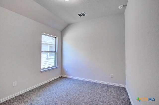 carpeted empty room featuring lofted ceiling