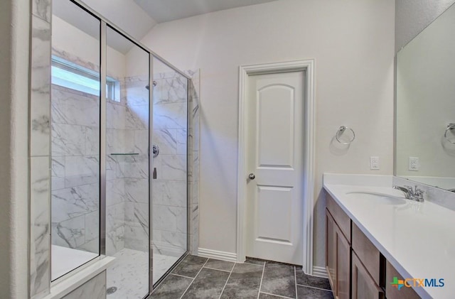 bathroom with a tile shower, vanity, and tile patterned floors