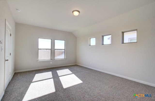 carpeted empty room featuring vaulted ceiling