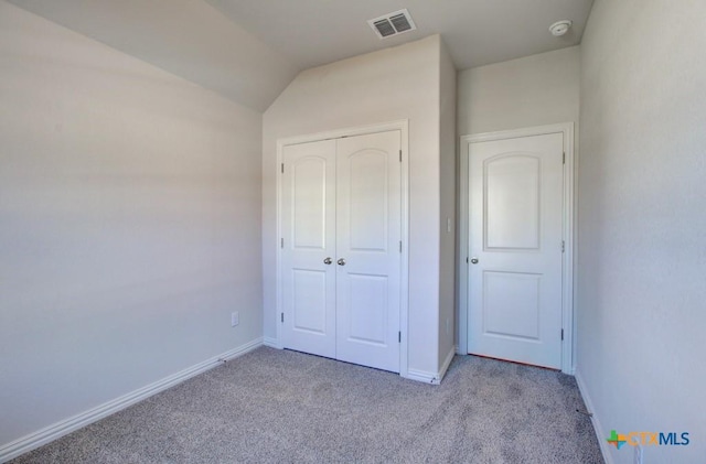 unfurnished bedroom featuring a closet, light colored carpet, and vaulted ceiling