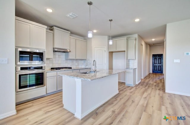 kitchen featuring decorative backsplash, light wood-type flooring, stainless steel appliances, sink, and decorative light fixtures