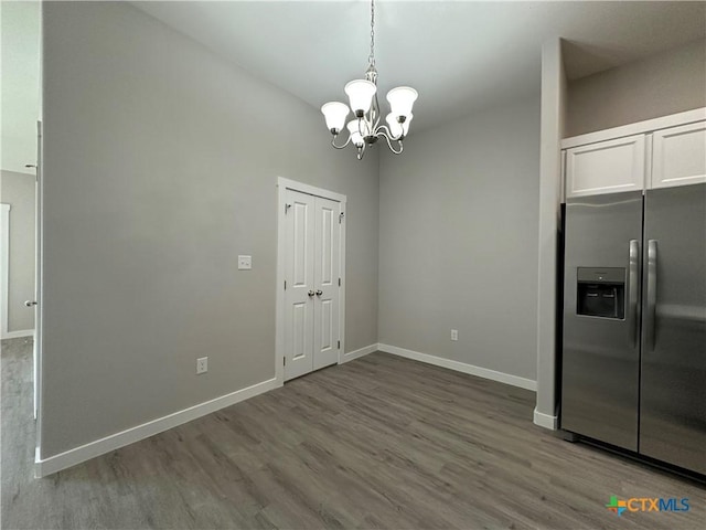 unfurnished dining area featuring hardwood / wood-style flooring and an inviting chandelier